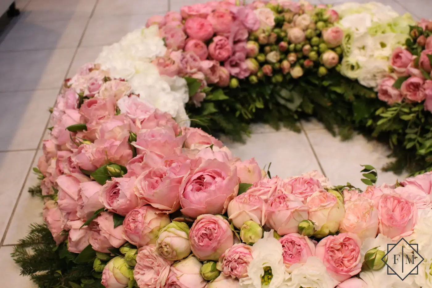 Impozáns, rózsaszín angol rózsákkal borított nagy méretű görög koszorú, hogy méltón emlékezhessenek meg az elhunytról. Ezek a gyönyörű virágok a barátságot, szeretet fejezik ki, így segítenek, hogy mindenki a legszebb pillanatait idézhesse fel az elhunyttal; Segítünk Neked, hogy a búcsú a lehető legszebb és legszemélyesebb legyen. Mond el nekünk, milyen ember volt az elhunyt, mit szeretett, hogyan élt. Mi gondoskodunk róla, hogy ez kifejeződjék a virágkompozíciókban.