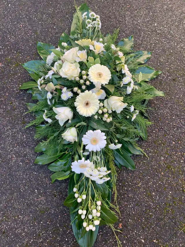 Klasszikus kialakítású sírcsokor fehér színű vegyes virágokkal, örök zöldekkel és vízutánpótlással növényeknek. A búcsú személyesebbé tehető, ha kegyeleti csokorba kéred elhunyt kedvenc virágait.