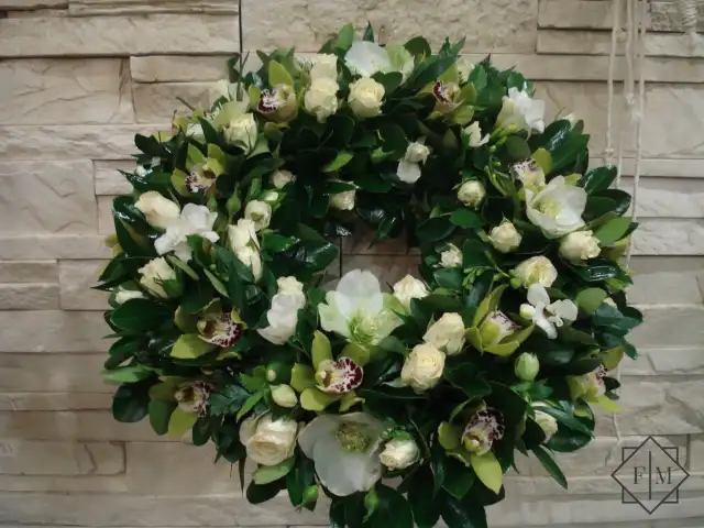 Nagyobb méretű, klasszikus görög koszorú zöld, fehér színvilágban. Méltó választás búcsúzásra kedves, visszafogott emberrel; Segítünk Neked, hogy a búcsú a lehető legszebb és legszemélyesebb legyen. Mond el nekünk, milyen ember volt az elhunyt, mit szeretett, hogyan élt. Mi gondoskodunk róla, hogy ez kifejeződjék a virágkompozíciókban